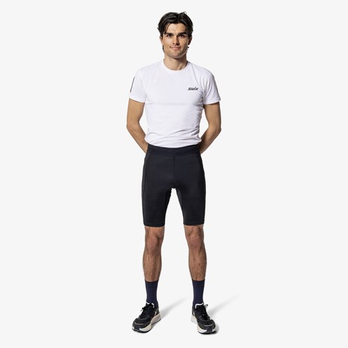 En mann if&#248;rt hvit skjorte og svart shorts.